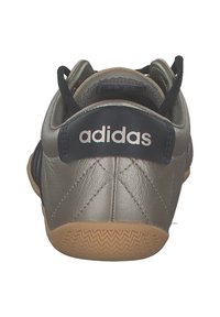 Baskets de sport en cuir gris avec un talon en tissu noir contrastant, dotées d'une semelle extérieure en caoutchouc gomme texturé et du logo "adidas" à l'arrière.