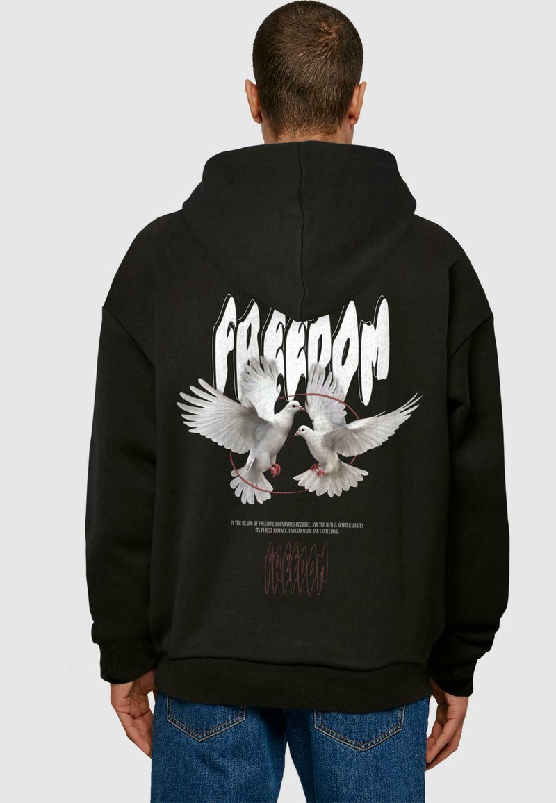 Felpa oversize nera con grafica di due colombe e la parola "LIBERTÀ" in grassetto bianco. Polsini e orlo aderenti con dettagli di cucitura.