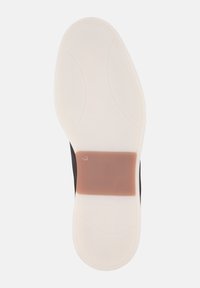 Semelle de chaussure avec une base blanche flexible, accent brun au centre, et texture lisse. Présente un design courbé pour le confort. Taille 43 visible.
