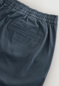 Dunkelblaue elastische Hosen mit glatter Textur, ausgestattet mit einer Gesäßtasche und dezenten Nähten. Schlichtes, lässiges Design.