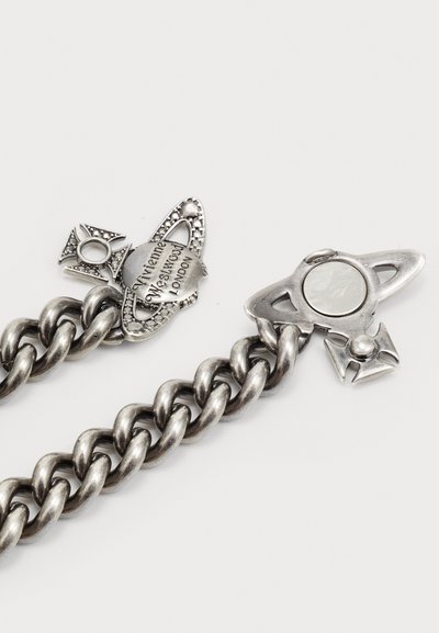 Bracciale in metallo argentato con link intricati, dotato di una chiusura decorativa a forma di pianeta stilizzato e dettagli incisi.