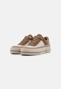 Bruin en crème lage sneakers van suede en leer, met een ronde neus, vetersluiting en een gestructureerde rubberen zool.