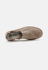 Zapato beige de tipo slip-on con una parte superior de algodón suave, suela de estilo mimbre tejida y una marca ecológica verde en la plantilla.