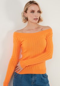 Pulover cu umerii goi, din tricot cu textura ribbed, într-o nuanță vibrantă de portocaliu, având mâneci lungi și o siluetă ajustată.