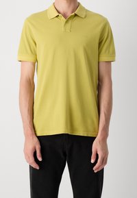 Polo vert citron en coton doux avec un col classique, deux boutons et un logo discret sur la poitrine. Manches courtes et ourlet droit.