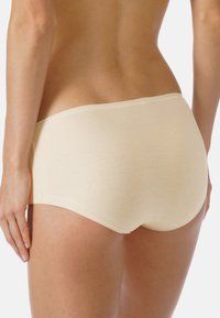 Shorts en coton beige pour garçons, au design sans couture et avec une taille élastique, affichant une texture lisse et un ourlet arrière arrondi.