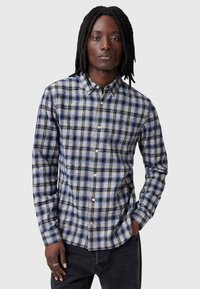 Overhemd met knopen in blauw, beige en zwart geruit. Lange mouwen, kraag en knoopsluiting aan de voorkant. Zachte textuur met een relaxte pasvorm.