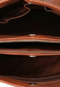 Interno di una borsa di pelle marrone vuota che mostra diversi scomparti con zip e foderatura scura.