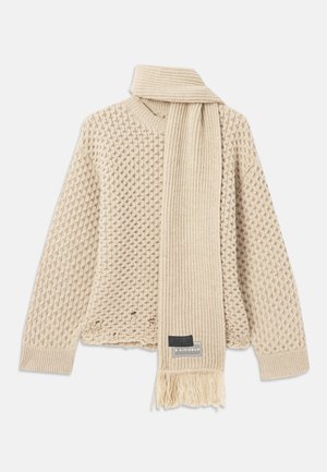 Pull en tricot beige texturé avec une écharpe côtelée assortie, présentant une frange et une étiquette de marque, les deux posés à plat sur un fond blanc.