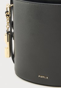 Čierna kožená kabelka s textúrovaným povrchom, kovovými zlatými doplnkami, reliéfne vytlačeným logom a dekoratívnym príveskom s kľúčom.