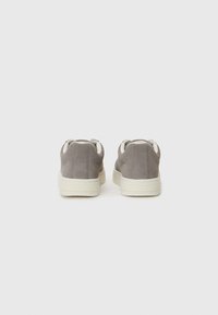 Gray suede sneakers with a rounded shape, cream rubber sole, and dual heel loops for easy wear. Minimalist design with star accents on the sides.
