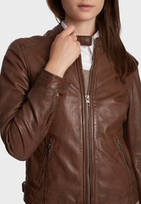 Bruine leren jas met een gladde textuur, ritssluiting aan de voorkant, drukknoopkraag en zijzakken. Heeft een getailleerde pasvorm en een minimalistisch ontwerp.