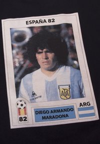 T-shirt met grafische print van een voetballer in een lichtblauw en wit gestreept shirt, met tekstlabels en een voetbalicoon.