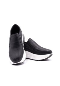 Czarne skórzane buty wsuwane o gładkim wykończeniu, z białą podeszwą środkową i teksturowaną podeszwą zewnętrzną, z okrągłym noskiem i niskoprofilowym designem.