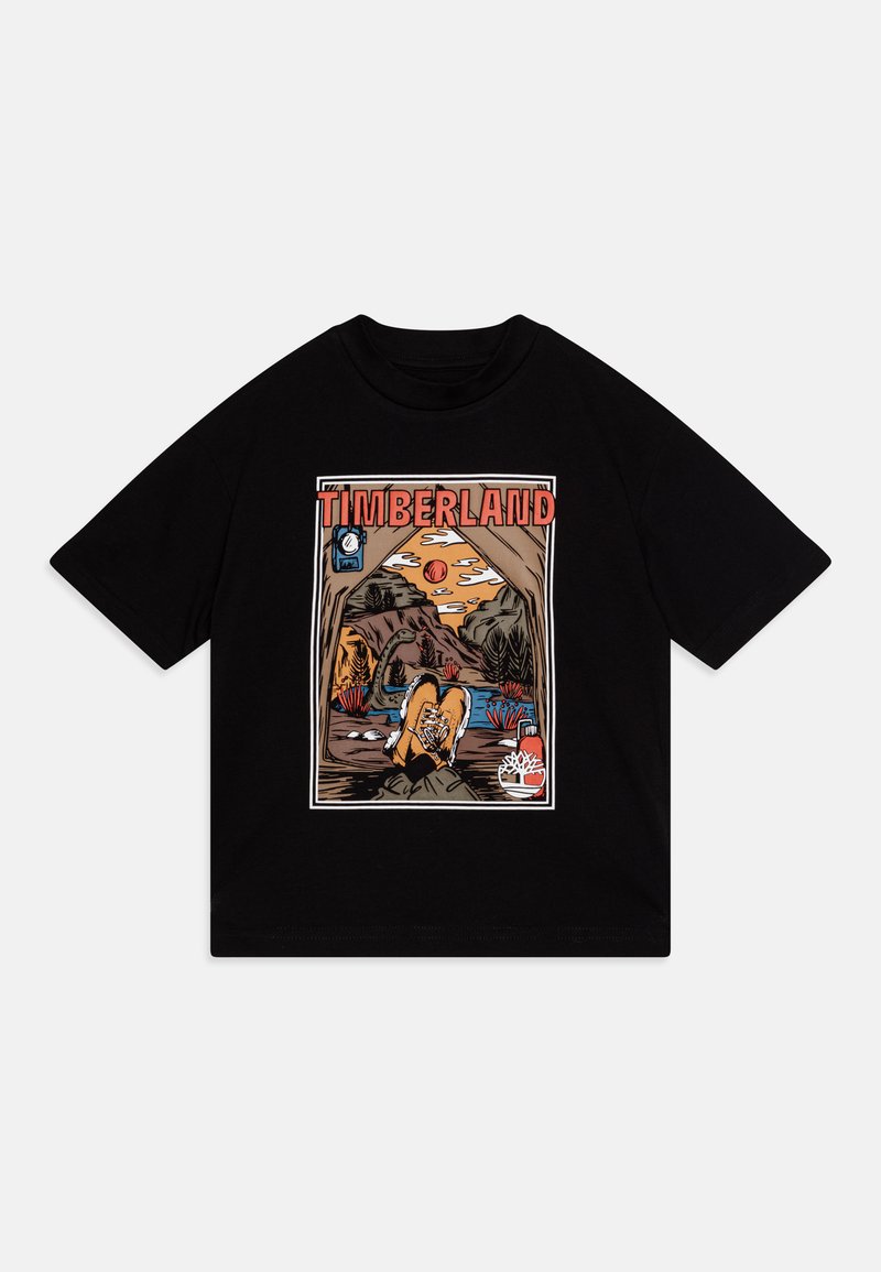 T-shirt nera in cotone con una grafica a fumetti colorata che presenta il testo "TIMBERLAND" e una scena naturale, inclusi stivali, montagne e elementi acquatici.
