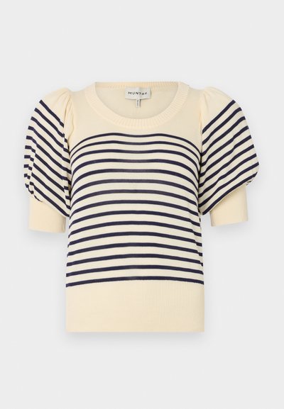Kremgenser med marineblå horisontale striper. Har korte puffermer og en rund ribbestrikket halslinning. Myk strikket materiale.