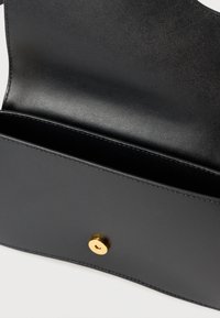 Schwarzes Lederportemonnaie mit glatter Textur, ausgestattet mit einem goldenen Druckknopfverschluss und einem offenen Fach zur Aufbewahrung.