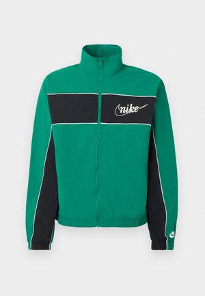 Πράσινο και μαύρο μπουφάν Nike με φερμουάρ, λευκά τιράντες, ψηλό γιακά, ελαστικά τελειώματα στα μανίκια και στη μέση, και λογότυπο Nike στο στήθος και το μανίκι.