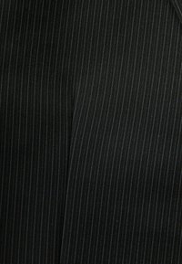 Czarna tkanina z wąskimi prążkami w jaśniejszym odcieniu. Teksturowana powierzchnia z gładkim wykończeniem. Odpowiednia do eleganckiego ubioru.