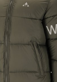 Olivgrön puffjacka med horisontell sömnad, framdragkedja, sidoficka och vitt logo på ärmen. Slät, isolerad tyg.