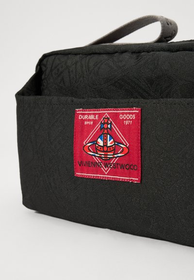 Schwarze Stofftasche mit strukturierter Oberfläche. Verfügt über ein rotes Etikett mit einem Logo und Text sowie einem grauen Tragegurt.