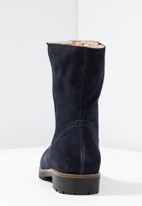 Námořnické semišové kotníkové boty s měkkou kožešinovou podšívkou, plochou gumovou podrážkou a tonálním prošíváním po stranách pro větší detail.