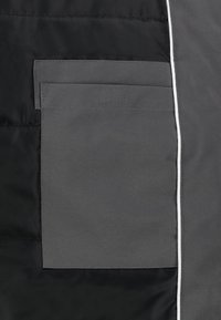 Gray puffer jacket section featuring a flat pocket, smooth texture, and white piping along the edge, set against a black background.