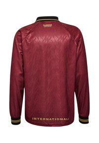 Bordo toonides pikkade varrukatega spordijakk musta ja kollase krae ning mansettidega, "hummel" logo ülaosas seljal, alumises osas tekst "INTERNATIONALS".