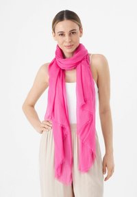 Heldere roze sjaal gemaakt van lichtgewicht stof, met rafelige randen en een vloeiende uitstraling, om de nek van het model gedrapeerd.