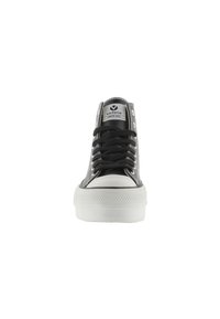 Zapatillas negras de caña alta con una puntera blanca de goma, cordones negros y una suela texturizada blanca. Marca visible en el lateral y en la lengüeta.