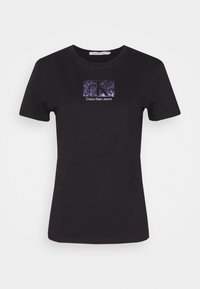 Camiseta de algodón negra con mangas cortas, cuello redondo, que presenta un logo blanco de Calvin Klein Jeans y un acento rectangular texturizado.