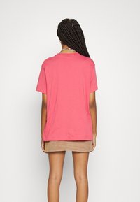 Rosa kortärmad t-shirt med avslappnad passform, mjuk textur och rundad halsringning, bärs med en brun manchesterminikjol.