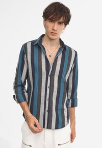 Striped button-up shirt featuring dark blue, teal, and gray vertical stripes. Long sleeves, single chest pocket, and a relaxed fit.