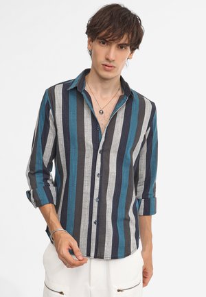 Camisa de botón a rayas con rayas verticales en azul oscuro, verde azulado y gris. Manga larga, un bolsillo en el pecho y corte relajado.