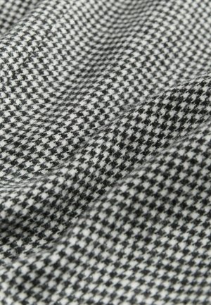Vävt tyg med ett houndstooth-mönster i svart och vitt. Mjuk textur med en lätt glans, vikt för att visa djup och dimension.
