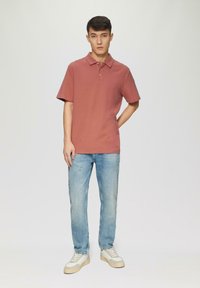 Korte mouwen, vervaagde rozenkleurige polo met drie knopen, gecombineerd met lichtblauwe rechte spijkerbroek en grijs-witte sneakers. Eenvoudig ontwerp.