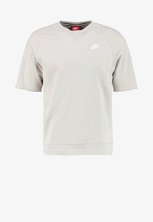 Ljusbeige Nike t-shirt med kort ärm, rundad halsringning och vitt Nike-logotyp på vänster bröst.