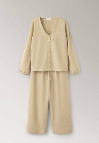 Ensemble de vêtements d'intérieur beige texturé deux pièces avec haut boutonné à manches longues et pantalon à jambes larges sur fond clair.