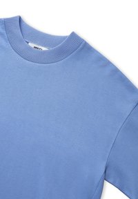 Světle modrý sweatshirt s kulatým výstřihem, ribbovaným límcem a hladkým, mírně texturovaným materiálem. Krátké rukávy a žádné viditelné grafiky nebo vzory.