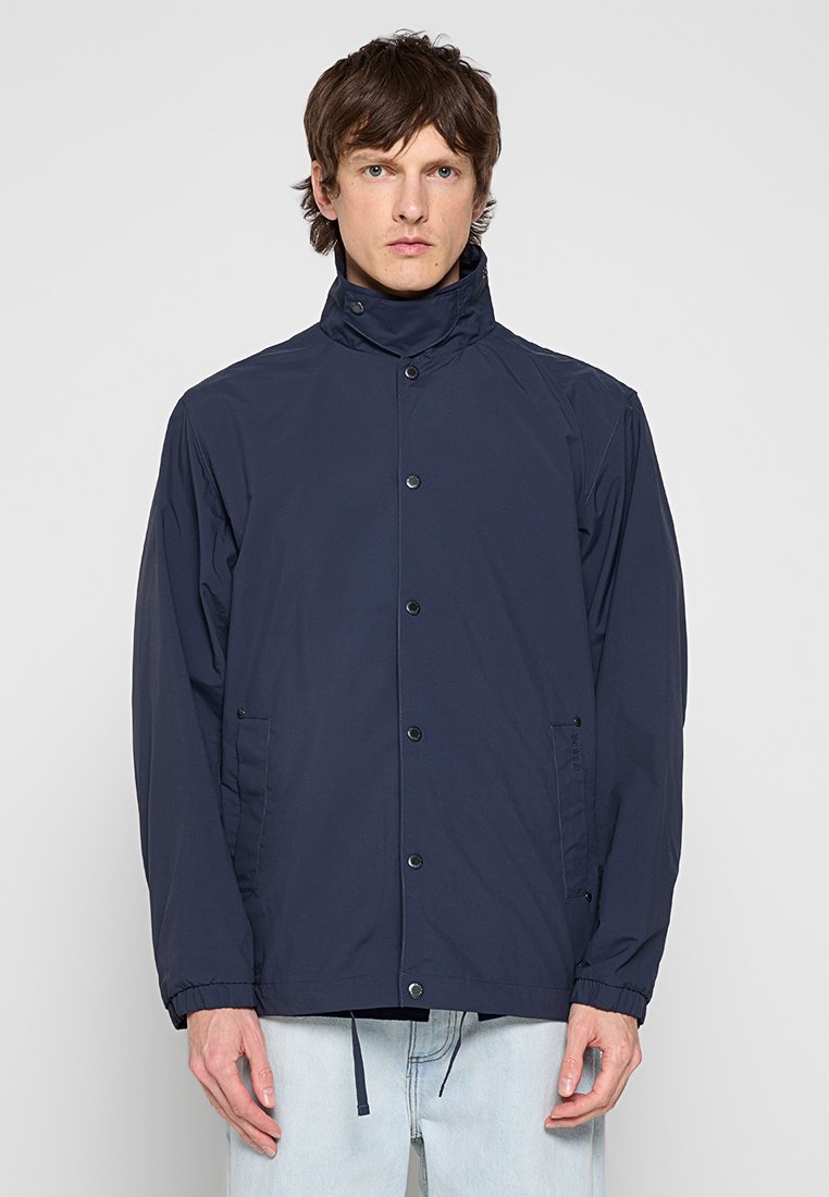 Marineblaues Jackett aus leichtem Stoff. Merkmale sind ein hoher Kragen, Druckknöpfe, elastische Bündchen und zwei Seitentaschen zur Aufbewahrung.