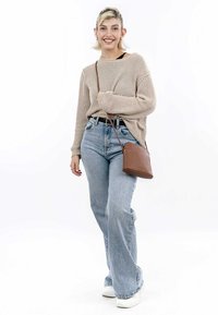 Pull en maille beige, jeans évasés taille haute bleu clair, baskets blanches et petit sac bandoulière marron. Texture lisse, coupe décontractée.