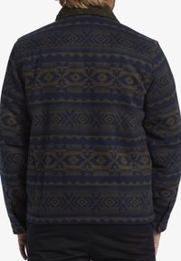 Navy blue patterned jacket with geometric designs in beige. Features a dark fuzzy collar and a soft texture. Buttoned back with long sleeves.