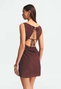 Abito mauve senza schienale in tessuto testurizzato, con scollatura a barchetta, chiusure a lacci regolabili e silhouette aderente.