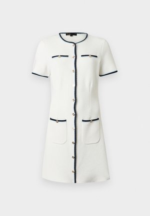 Robe blanche à manches courtes avec bordure marine, boutons dorés sur le devant, deux poches poitrine et deux poches sur les hanches, longueur au genou, encolure ronde.