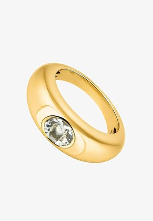 Anillo de metal dorado con un diseño suave y redondeado; presenta una piedra preciosa ovalada y transparente engastada en un bisel.