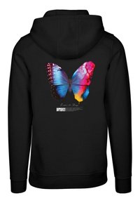 Un sweat à capuche noir avec un graphique de papillon coloré en bleu, rose et jaune. Le texte en dessous indique "Devenu pour changer PAPILLON."