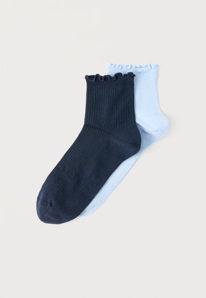 Dvi dygliuotos kulkšnies kojinės su raukšlėtomis apykaklėmis, viena tamsiai mėlyna, dėvima ant šviesiai mėlynos kojinės, ant paprasto šviesaus fono.