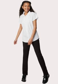 Wit overhemd met korte mouwen en kraag, gecombineerd met zwarte broek met rechte pijpen. Zwarte schoenen met glanzende afwerking maken de outfit compleet.