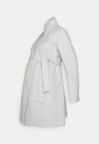 Grijze wollen zwangerschapsjas met een wikkelontwerp, zijstrikceintuur en kraag. Kenmerkt zich door een licht uitlopende A-lijn en lange mouwen.