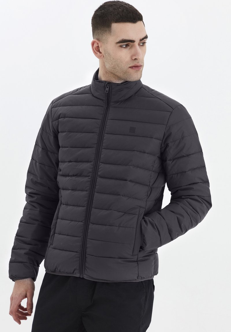 Svart vadderad jacka med hög krage och dragkedjestängning, som har horisontellt quiltade sektioner och en lätt design.